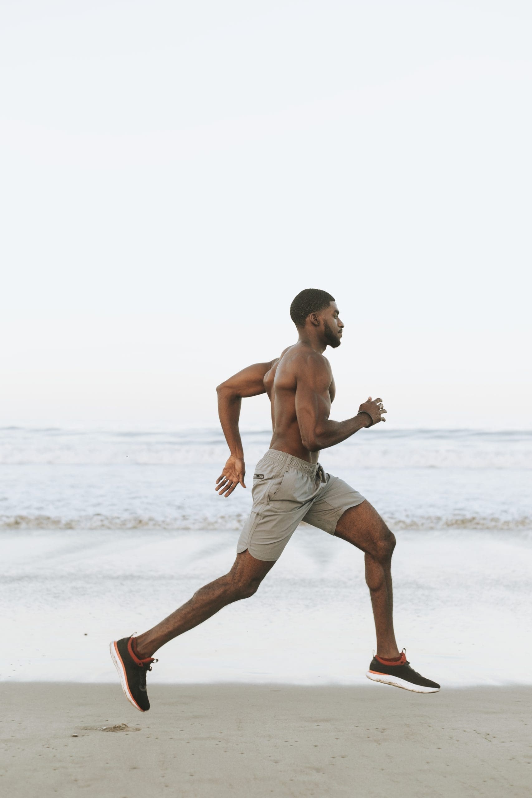 Hombre en forma corriendo por la playa a primera hora de la mañana